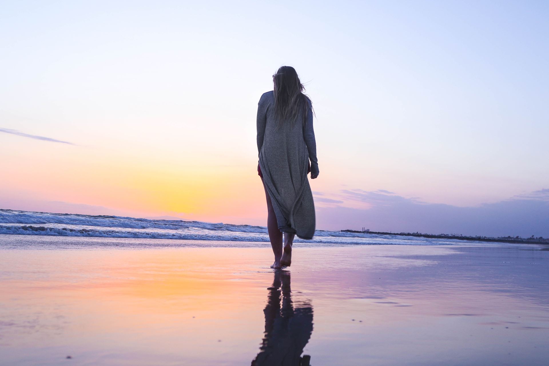 a silhouette of a woman on a beach looking out to sea